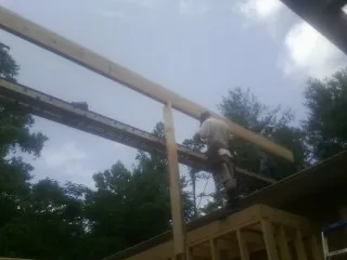 Carpenter setting a ridge beam over a new addition frame — Ice Dam Removal by Roofing Brothers in Blakeslee