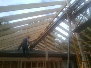 Rafters going up over a new addition with a worker on the wall in Blakeslee