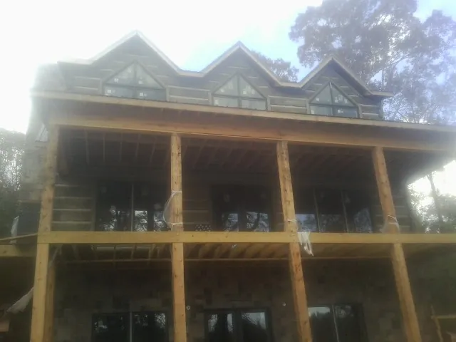 Dormers and porch framing on a large log home under construction — Roof Coating work by our crew in Blakeslee