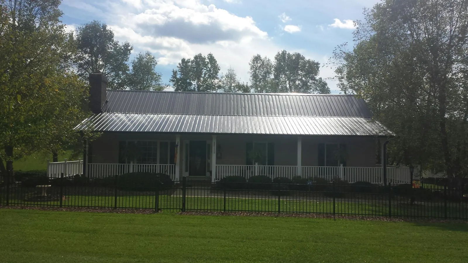 Gray metal roof on a brick ranch with a full width front porch — Gutter Guard Installation work by our crew in Blakeslee