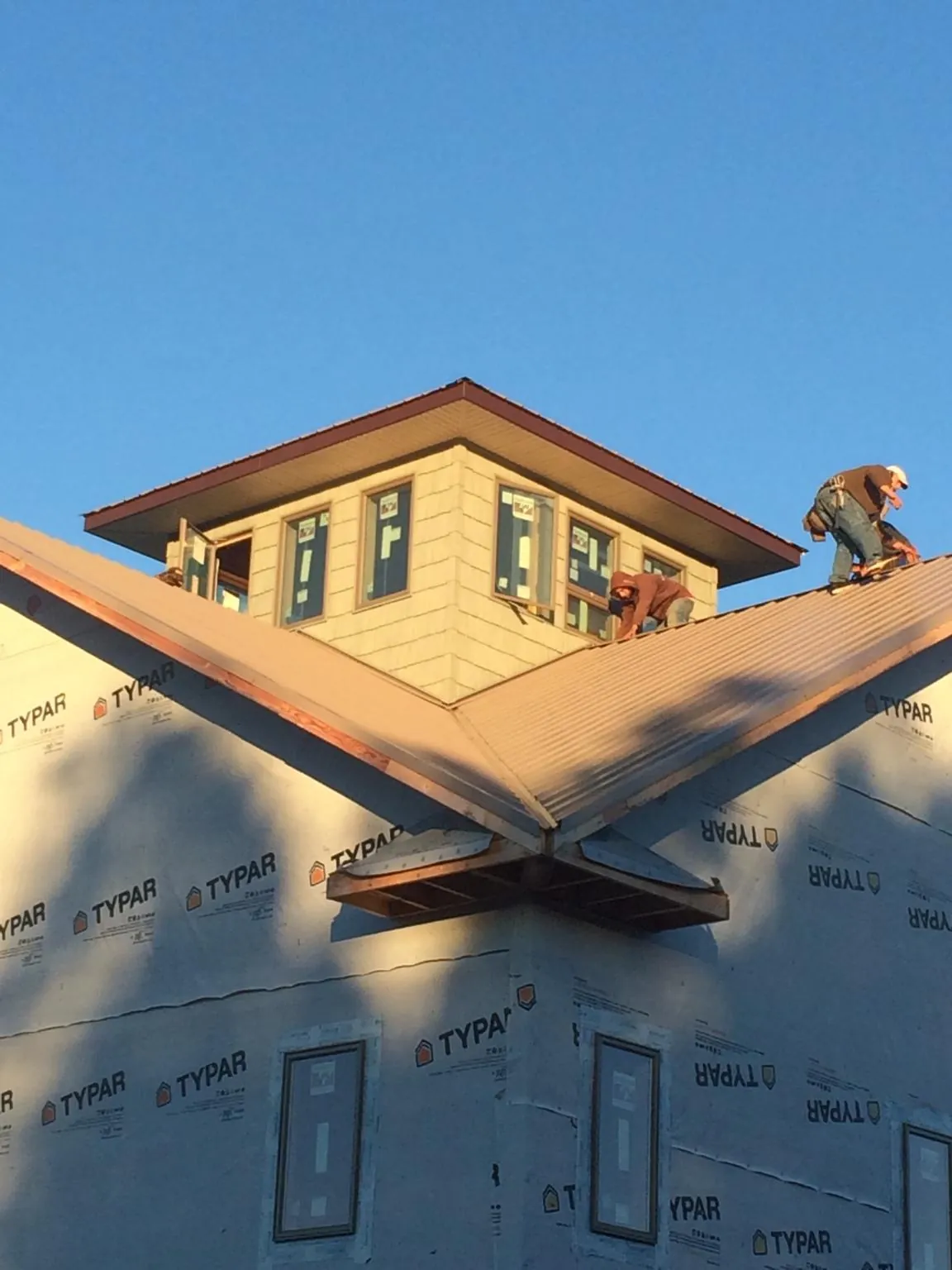 Roofers working around a rooftop cupola on a new metal roof at sunset — Roof Waterproofing in Blakeslee by Roofing Brothers